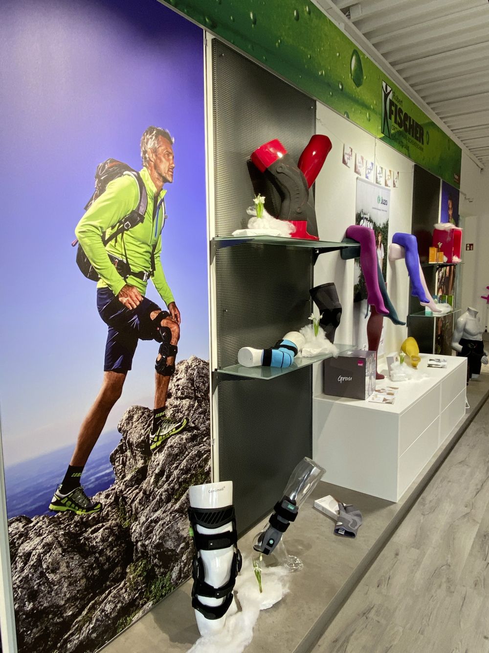 Wandabwicklung im Sanitätshaus für Orthopädietechnik. Mit grünen Akzenten, die das Firmenfarbschema widerspiegeln, bieten diese Regale ein ästhetisch ansprechendes Erscheinungsbild.