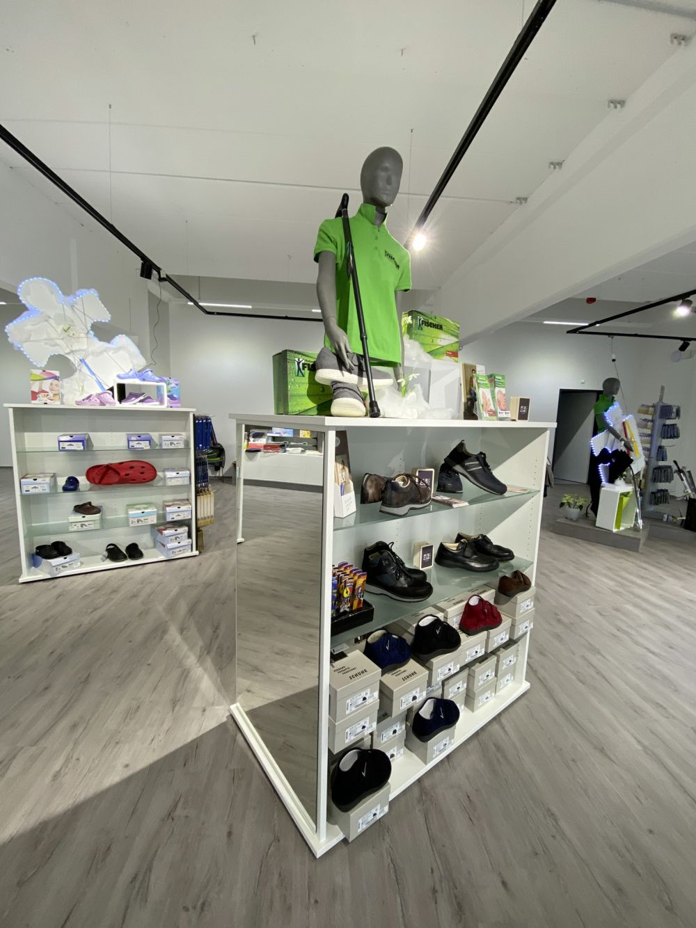 Freistehende Warenträger mit stilvoll präsentierten Schuhen – funktional platziert für eine bequeme Anprobe.