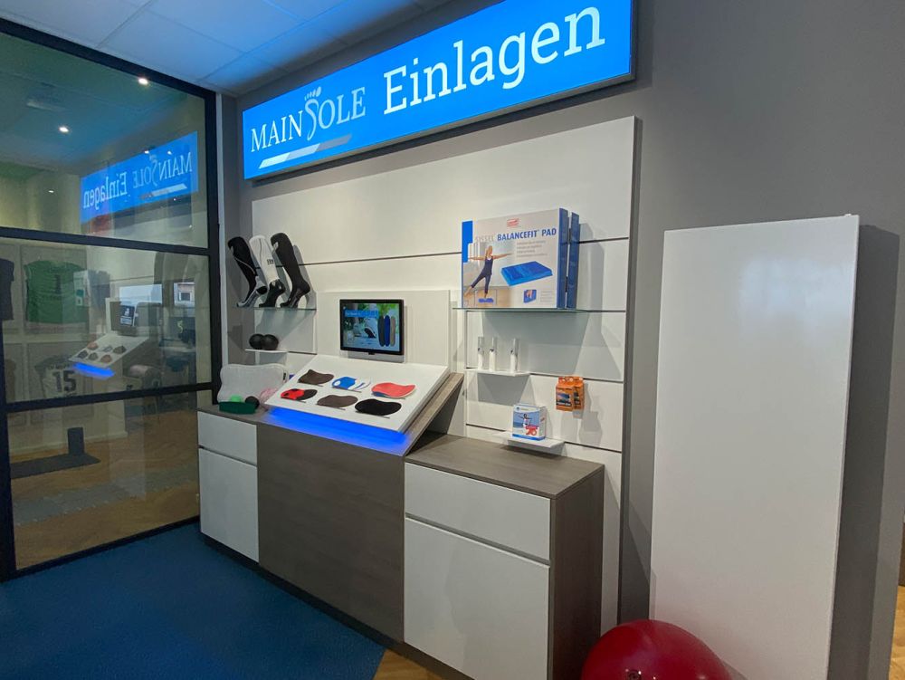 Ein maßgefertigtes Wandmodul mit integriertem Bildschirm dient der digitalen Präsentation verschiedener Einlagentypen. Die Kombination aus moderner Technik und funktionalem Design unterstützt eine anschauliche, kundenorientierte Beratung im Sanitätsbereich.